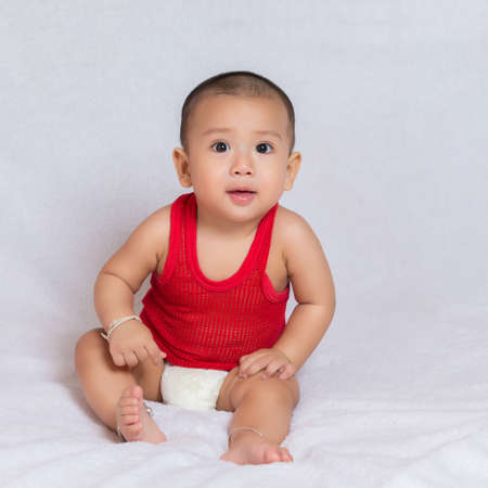 Happy baby wearing red t-shirt.Cute kids in a good mood Sit down on the couchの写真素材