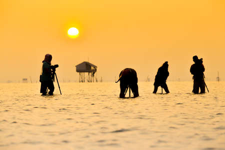 Silhouette of a photographer with tripod on beautiful tropical sunsetの写真素材