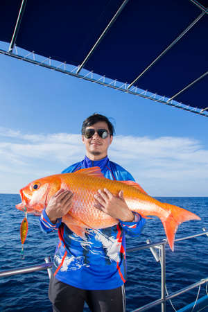Lucky fisherman holding a beautiful goldfishの写真素材