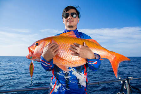 Lucky fisherman holding a beautiful goldfishの写真素材