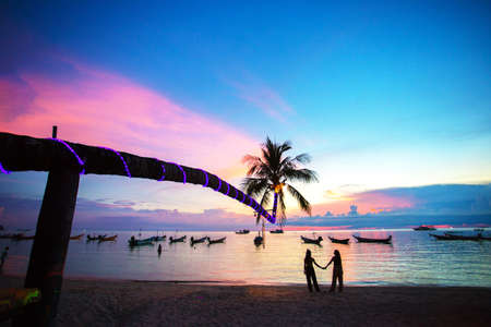Coconut silhouette with sunset sea,Boats at sunset and palm to the seaの写真素材