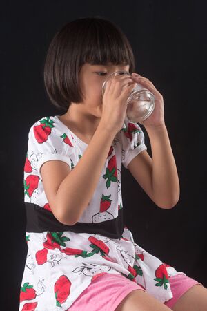 girl is holding a glass of water on blakgroundの写真素材