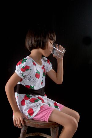 girl is holding a glass of water on blakの写真素材