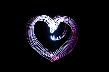 Heart created by light over black background  の写真素材
