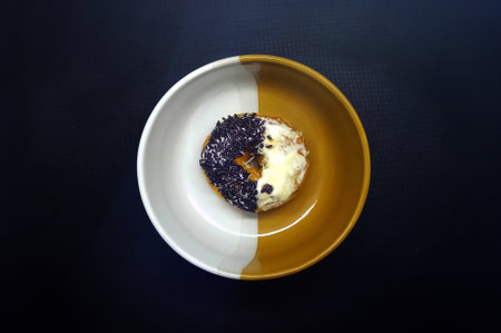 donut on a plate on a black background, closeup of photoの写真素材