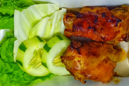 Thai style grilled chicken on the plate with cucumber and lettuceの写真素材