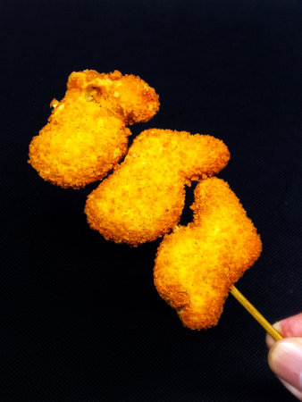 Fried chicken nuggets on a stick on a black background.の写真素材