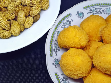Deep-fried peanuts on a plate with a bowl of peanuts.