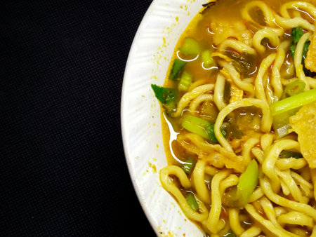 Thai noodle soup with pork and vegetable in white bowl on black backgroundの写真素材