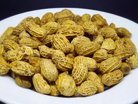 peanuts in a white plate on a black background close-upの写真素材