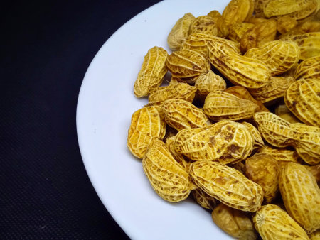 Peanuts in a white plate on a black background. Close-up.の写真素材