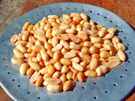 Peanuts on a metal plate on a wooden table.の写真素材