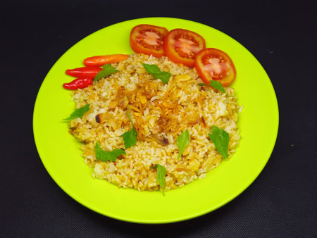Rice with meat and vegetables on a green plate on a black backgroundの写真素材