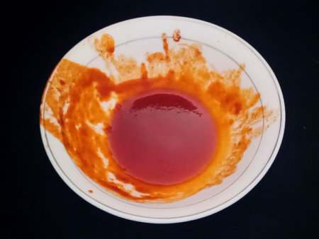 Ketchup stains in a bowl on a black background, top viewの写真素材