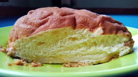 A fresh, sliced loaf of bread displayed on a green plate, suitable for bakery, food blog, or...