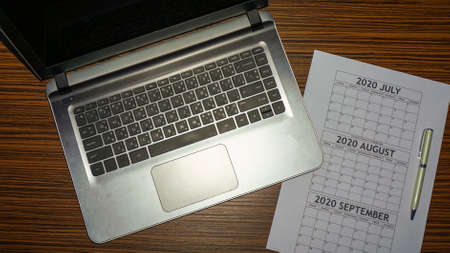 Business Planning with laptop and calendar for July, August, September. Empty calendar with computer...