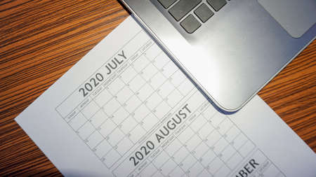 Business Planning with laptop and calendar for July, August, September. Empty calendar with computer notebook on a working table. Holiday planning.の写真素材