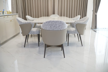 White and tan dining table with six chairs around it. The chairs are all different colors and...