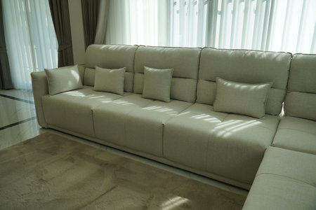 White couch with four pillows on it. The couch is in a living room with a tan carpet