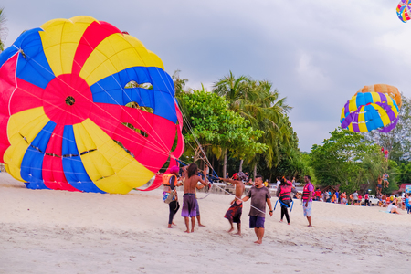Langkawi, Malaysia - February 13, 2016: A group of Malaysian people engaged in parachuting extreme sports on Pantai Tengah Beach, Langkawi island, Malaysia. Summer vacation and fun.のeditorial素材