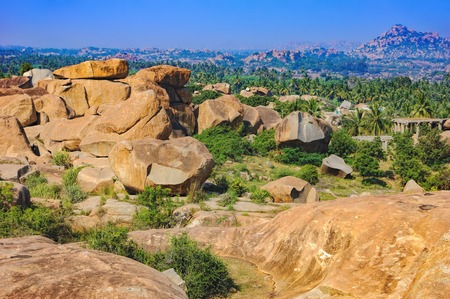 Landscape with unique mountain formation with amazing stones, palm trees and bushes in Hampi, Indiaの写真素材