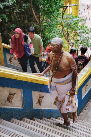 Batu Caves, Malaysia - February 7, 2016: Malaysian Hindu man in traditional dress walks up the steps to the Batu Caves. The cave is one of the most popular Hindu shrines outside Indiaのeditorial素材