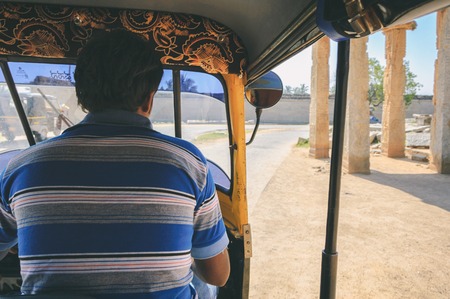 Hampi, India - November 11, 2012: Point of view shot from inside a moving tuk tuk. Street scene with ancient ruin of Hampi in motion blur on sandy and dusty roadのeditorial素材