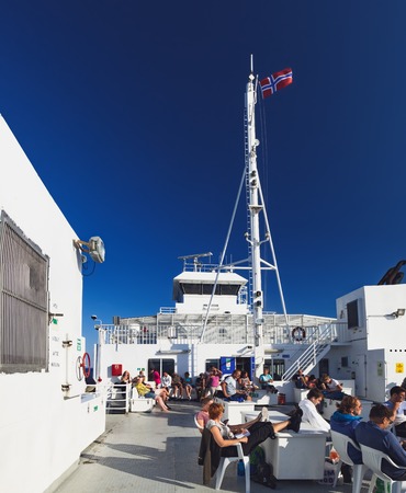 Bodo, Norway - July 28, 2018: Travelers sit on benches on the deck of the ferry while sailing from...