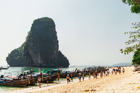 Railay, Thailand - February 15, 2018: Thai traditional long boats on crowded Phra Nang Cave Beach, Railay in Krabi province, Thailand. Tropical beach of Andaman Sea with walking tourists.のeditorial素材