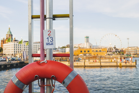 The iconic architecture of the Helsinki - Ferris wheel and Uspenski Orthodox Cathedral visible from the side of the pier, Finland. The name of the pier is written on the plate in the middleの写真素材