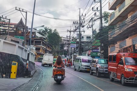 Phuket, Thailand - January 30, 2019: Tourists in swimsuits go to the beach on a bike, a typical view of the streets of Phuket, Thailandのeditorial素材