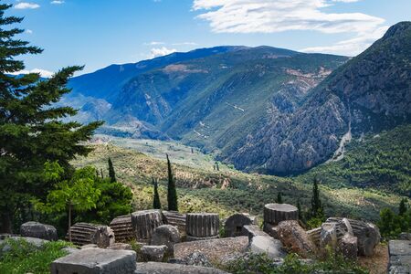 Scenic landscape with picturesque mountains, cloudy sky and ancient ruins on the Hillside of the Archaeological Site of Delphi, Greeceの写真素材