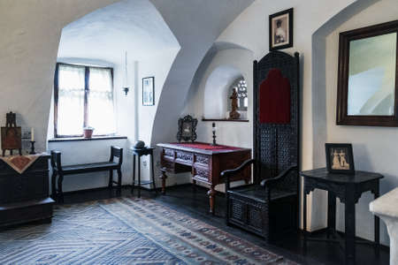 Bran, Romania - September 7, 2017: One of bed rooms in Bran or Dracula Castle in Transylvania, Romania. Antique carpet on floor, wooden chairs, furniture itemsのeditorial素材