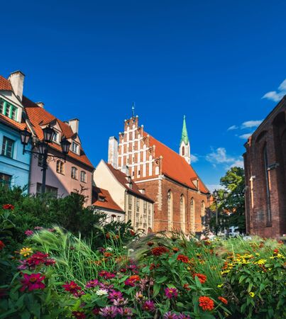 St John Church in Old Town of Riga, Latvia. Beautiful flowers in foreground and aged Latvian lutheran Church under blue skyの写真素材