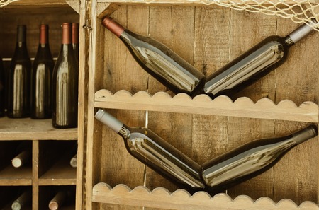 Red wine bottles stacked on wooden racksの写真素材