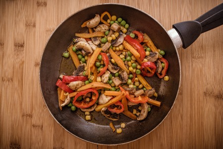 frypan and vegetables on wooden background