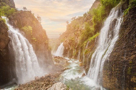 waterfall in mountain forest under great sky.の写真素材