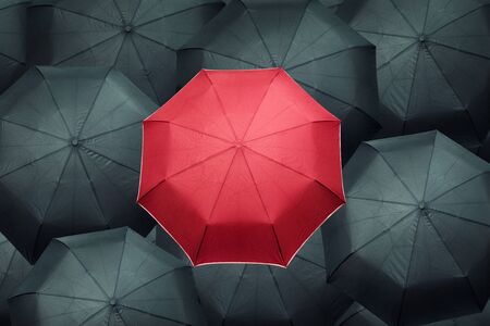 Red different umbrella over many black umbrellas. Business leadership concept.の写真素材