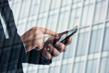 Closeup photo of businessman hands touching screen smartphone. blurred background.
