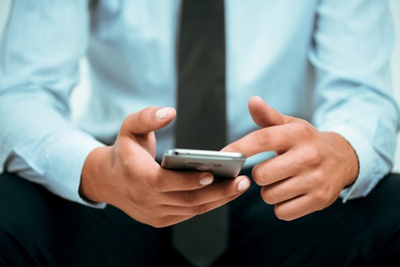 Closeup photo of businessman hands touching screen smartphone.の写真素材