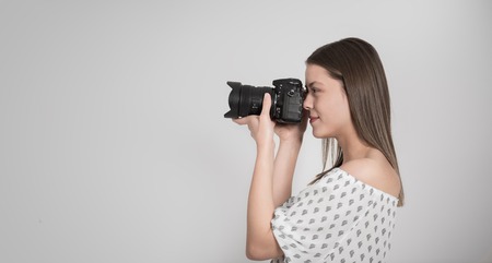 Woman photographer taking photograph against grey backgroundの写真素材