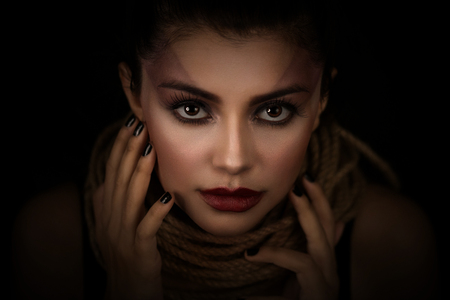 Portrait of young woman over rope with black background. Fashion, extraordinary makeup and face lifting concept.の写真素材
