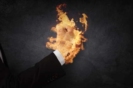 Close up of businessman hand holding fire in fistの写真素材