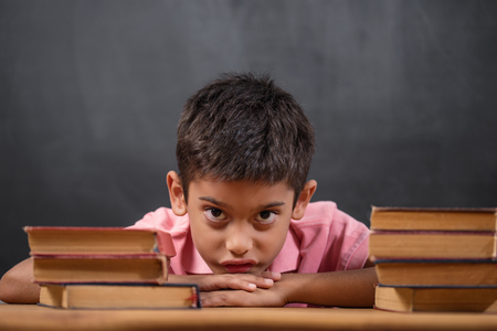 Thoughtful cute clever boy with book on table. First time to school. Back to schoolの写真素材