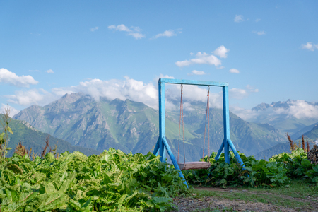 the old wooden swing for children in the yard. against mountainの写真素材