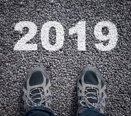 Happy new year 2019. man legs in sneakers standing on asphalt road and number 2019.
