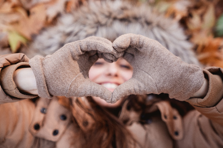 Woman making heart symbol with hands on nature.の写真素材