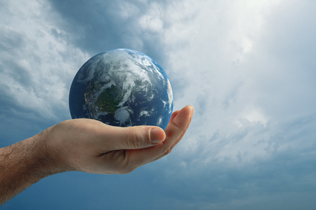 Globe in human hand against blue sky. Environmental protection concept.の写真素材