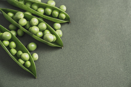 open pea pod with green beans in it. On a dark background