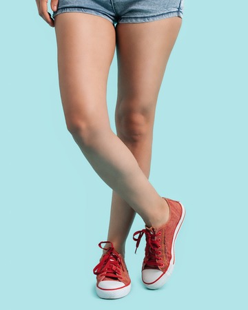 Woman wearing a red sneakers. On blue background.の写真素材